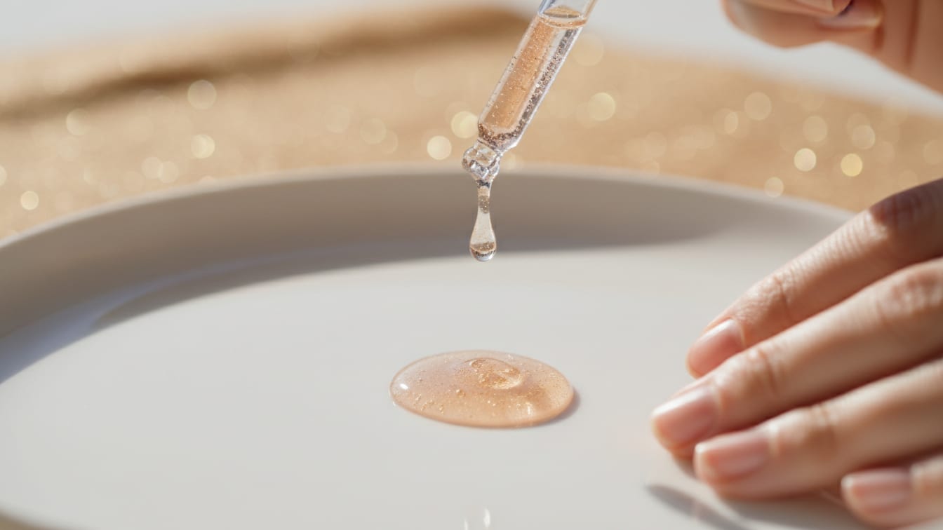 Illustration: A clear, viscous liquid drop suspended above a white ceramic surface, with subtle gold reflections.